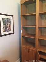 Full view of wooden book shelf with four shelves and two door cabinet showing oak finish and decorative top arch.