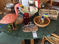 Overview photo showing all items on green table including flamingo statue, wooden bowls, ceramic fish bowl, glass bowls, wicker basket, and decorative plaque.