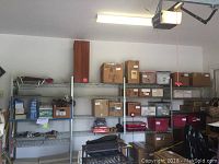 Overall view of four connected shelving sections in garage, loaded with boxes and miscellaneous items.