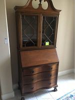 Full view of wooden Queen Anne style secretary desk with three drawers, pull-down desktop, and glass hutch with geometric muntin patterns.