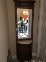 Front view showing the full height of the wooden entryway butler with embossed mirror and white marble top.
