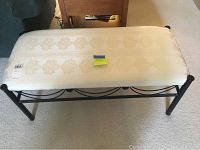 Front and side view of metal bench with cream damask patterned cushion top, showing metal frame and cushion condition.