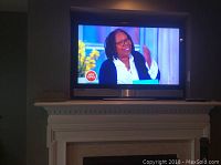 Front view of the Vizio television powered on, mounted above a fireplace mantle