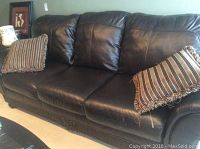 Full view of sofa showing three seat cushions, rolled arms, and two striped throw pillows.
