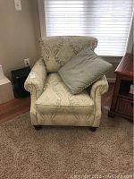 Front view of the upholstered chair with the accent pillow placed on the seat.