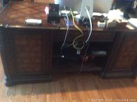 Front view showing entire desk including cabinets, open shelves, and connected wires for electronics on top.