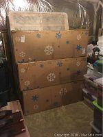 Three snowflake-patterned cardboard boxes stacked in basement environment
