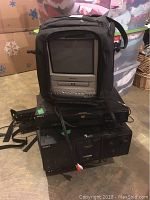 Stack of Sony electronics including small portable TV with DVD, Sony DVD player, CD player, and VHS player with some wiring visible, all black units.