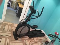 Full side profile of elliptical, showing frame and pedals