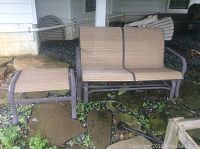 Outdoors glider bench with matching ottoman placed on stone and gravel surface, showing overall view of the lot items