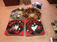 All four wreaths laid on the floor, showing two boxed Christmas wreaths and two unboxed seasonal wreaths (fall and spring).