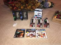 Full lot of sealed PlayStation Move and navigation controllers, three PS3 games, and two Afterglow Wii controllers on carpeted floor.
