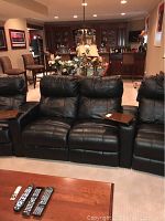 Front view of black leather recliners displaying headrests and tray surfaces