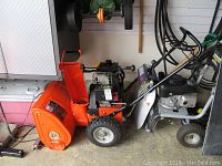 Left side view of orange Ariens 524 snow blower showing auger housing and controls