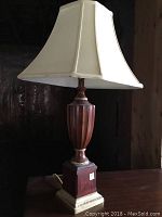 Full view of the table lamp showing the wood base, brass accents, and white fabric shade.