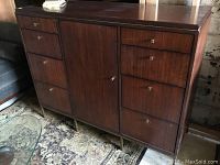 Front view of cabinet showing wood grain veneer finish, central door and drawers on each side