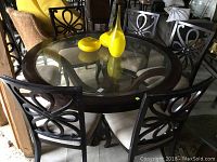 Full view of round glass-top dining table and six matching chairs in arrangement