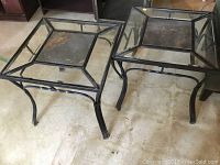 Two square end tables with iron frames, glass sides, and slate inserts on top.