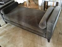 Full side angle showing the pewter grey day bed with bolster pillows on each end, upholstered in plush polyester fabric with wooden legs.