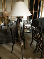 Full view of the tripod floor lamp showing wood legs, fabric shade and chrome hardware