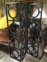 Full view of the black decorative folding screen with multiple panel sections and circular cutout design, showing its general size and structure.