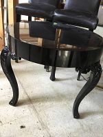 Front angle view showing the black lacquer finish and carved legs of the round table.