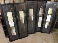 Full view of the 5 framed decorative pictures leaning against each other, showing their general appearance and size.