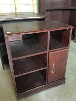 Front view of the cabinet showing open shelves and single door with metal handle.