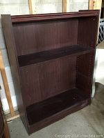 Front view of wooden shelf showing two shelves and open back with some wear and marks.