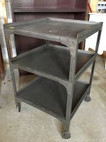 Front-side angle view of three-tier steel cart on caster wheels