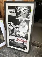 Framed comic book style artwork featuring black and white close-up faces with red text. Frame has marks and scratches; matting shows water damage.