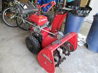 Side perspective showing red housing, two-stage auger and pneumatic tires