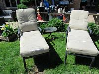 Overall view of both chaise lounges with cushions and side table in yard