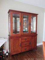 Full view of the assembled mission style buffet and hutch showing wooden construction, warm brown finish, glass doors on hutch, mirrored back, soft lighting on top, and metal hardware.