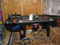 Full shot of the Mastergrip router table showing the entire working surface, fence, and included accessories in front showing clamps and guides.