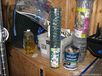 Shelf with rolls of green coated chicken wire fencing and galvanized chicken wire fencing along with a can of Valspar concrete stain.
