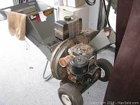 Photo showing full chipper shredder unit with hopper, engine, wheels, and attached collection bag.