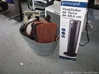 Photo of oscillating tower fan box next to metal container holding ceiling fan blades and housing.