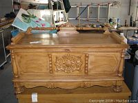 Front view of the Lane cedar chest showing ornate floral carvings, carved paneling, and turned legs.