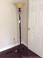 Full view of the floor lamp showing the base, pole, and shade in corner of room.