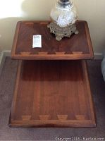 Top-down view showing the two-tier rectangular surfaces with inlaid wood detail on the edges. A lamp and lot tag present on the top tier.