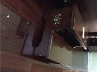 Side view of the nightstand showing drawer partially open and the bed step adjacent to it, both made of dark finished wood with visible signs of wear.
