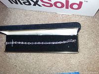 Sterling silver amethyst-colored bracelet laid inside a black velvet-lined rectangular box with MaxSold sign in the background.
