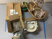 Lot displayed together showing boxed glassware, chip dish, baskets, and other kitchen decorative items.