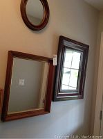 Photo showing three wall mirrors hung on the wall: one round, one medium rectangular, and one large rectangular mirror with visible price tag.