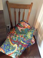 Wooden arrowback chair with a colorful handmade blanket draped over it