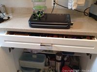 Food Saver vacuum sealing machine on countertop with parts and dehydrator trays stacked behind