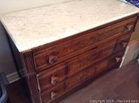 View of antique wooden dresser with three drawers and carved handles, marble top unattached