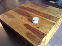 Top view close-up photo showing the wood grain and scratches on the coffee table surface with two round wooden coasters.