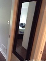 Full length mirror installed on a wall in a hallway showing its size and overall appearance.